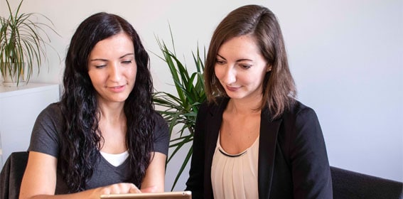 Physiotherapeutin Daniela zeigt einer Büroangestellten etwas am Tablet.